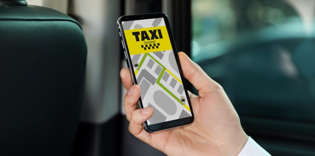 A photo of a hand holding a phone with a ride-hailing taxi app open